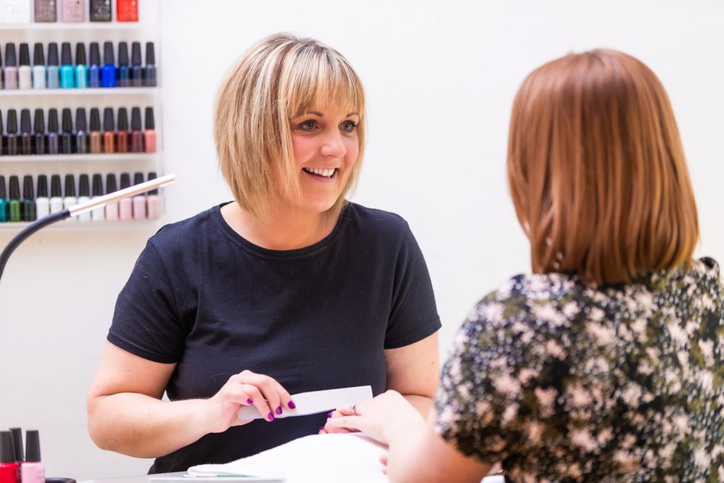 Beauty therapist filing a customer's nails