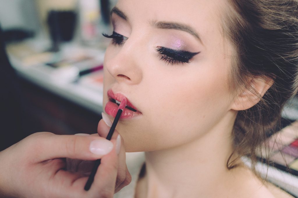Woman having lipstick applied by a stylist